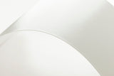 The image is a close-up of a white, curved surface, possibly a piece of paper or a fabric.