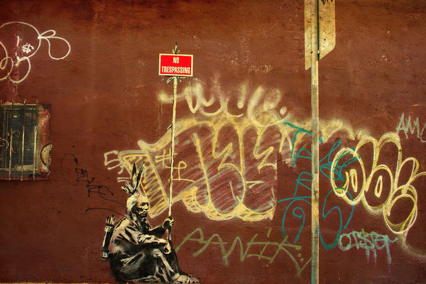 a man sitting on a bench in front of a wall covered in graffiti
